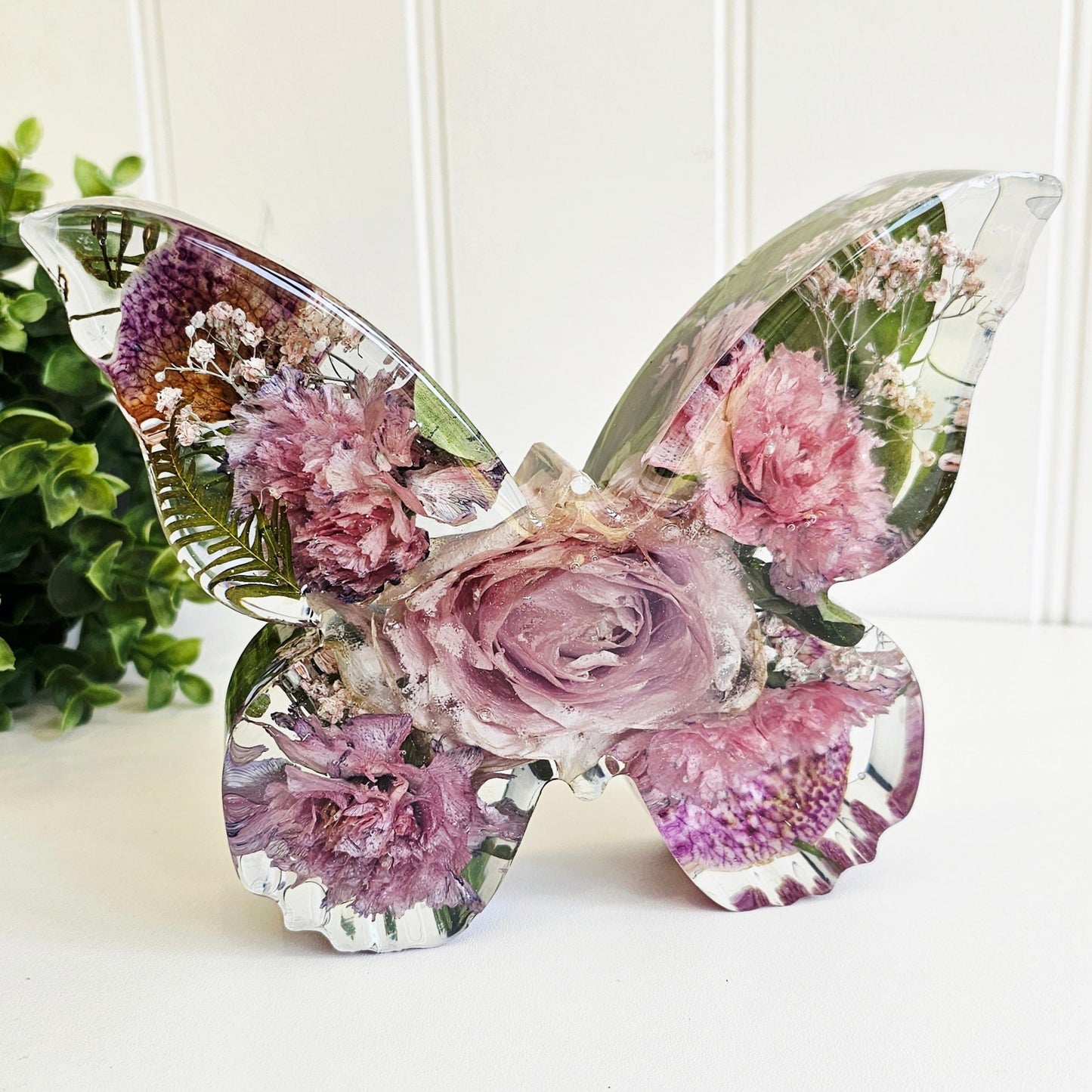 preserved funeral flowers in a butterfly shape resin ornament. a memorial keepsake