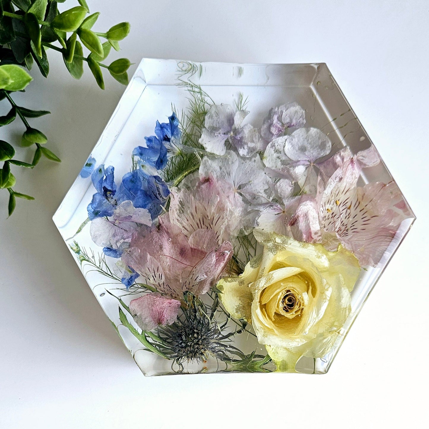 Hexagonal resin ornament with preserved flowers on a white surface