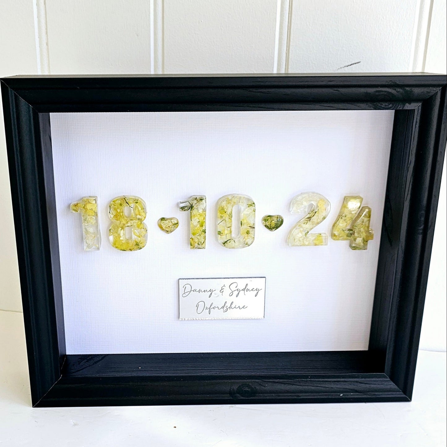 Framed artwork with gold numbers and personalized text on a white background