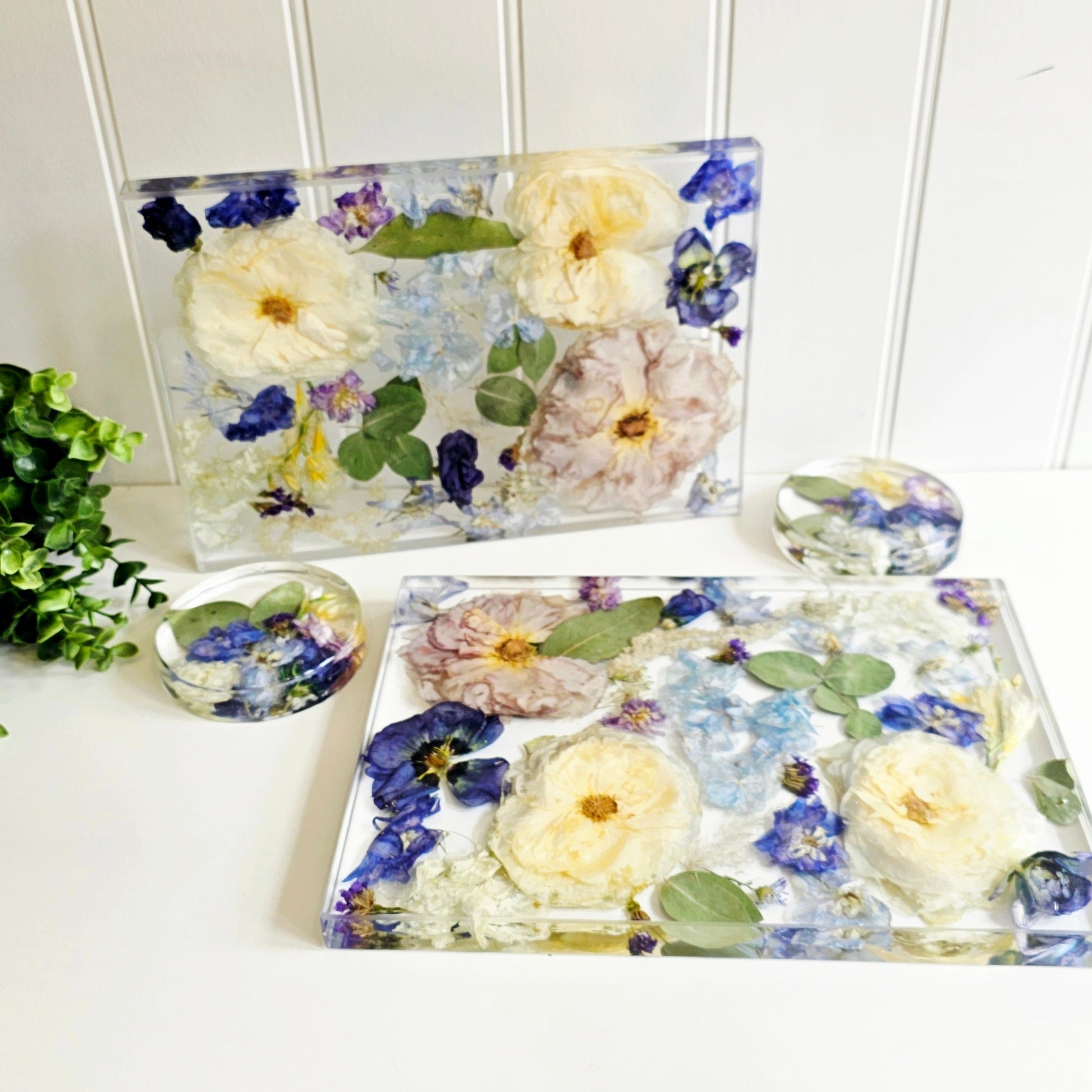 Set of floral coasters and place mats with pressed flowers on a white surface.