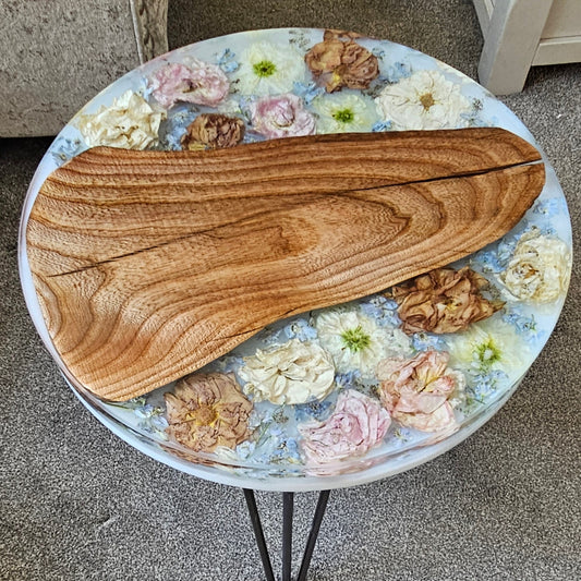 Round resin table with floral design and wooden top on a carpeted floor