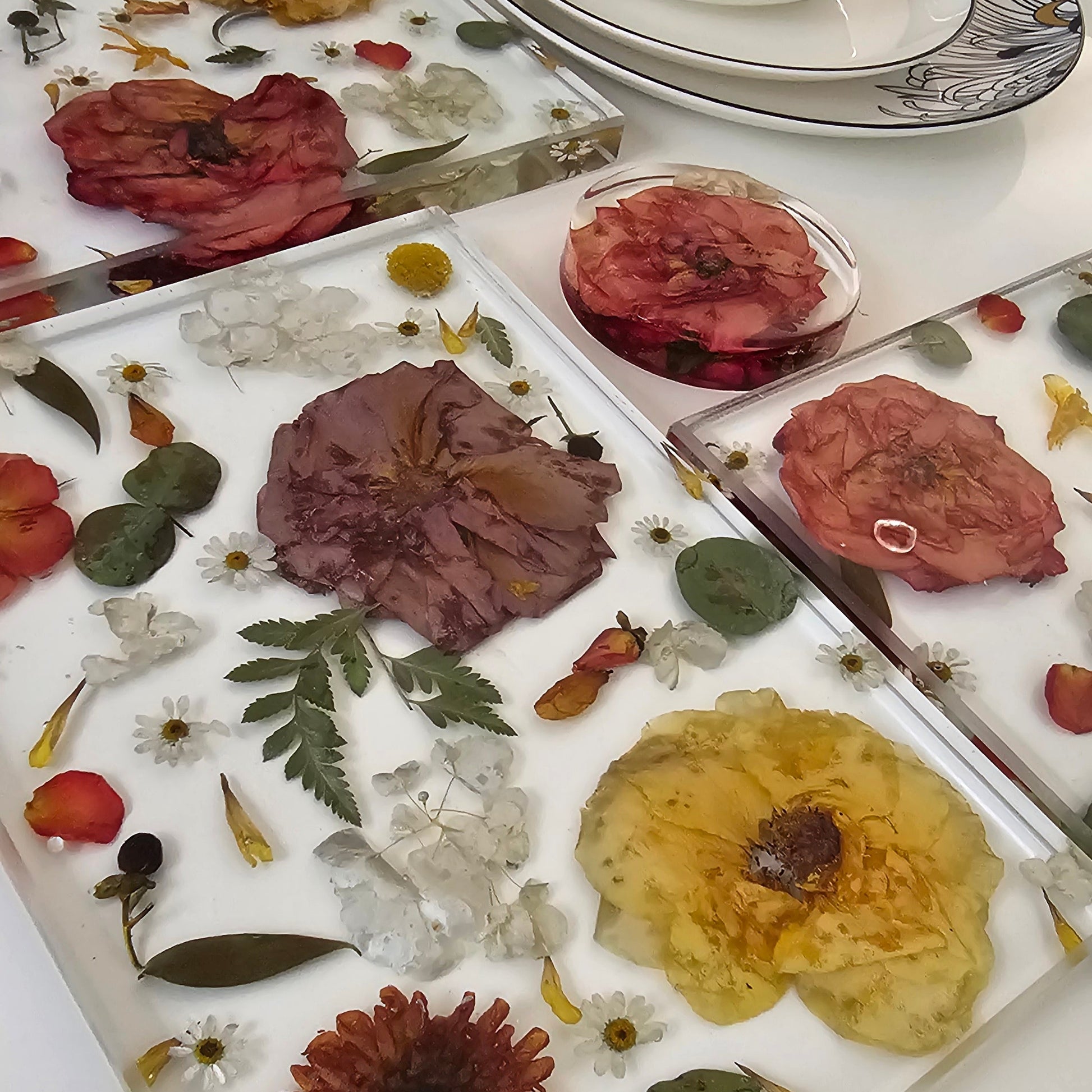 Resin placemats with pressed flowers and leaves on a white surface