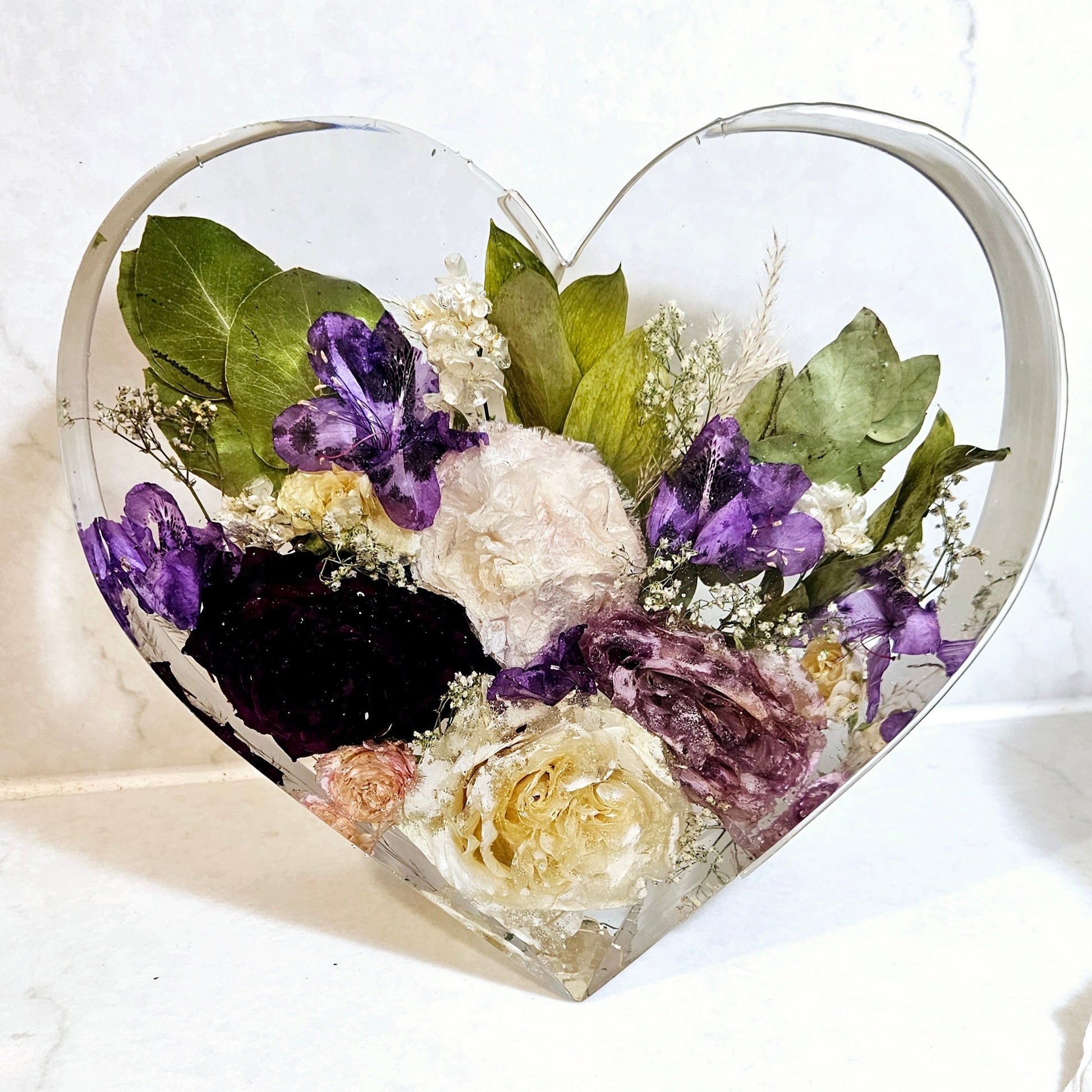 a wedding bouquet preserved in a resin in the shape of a standing heart