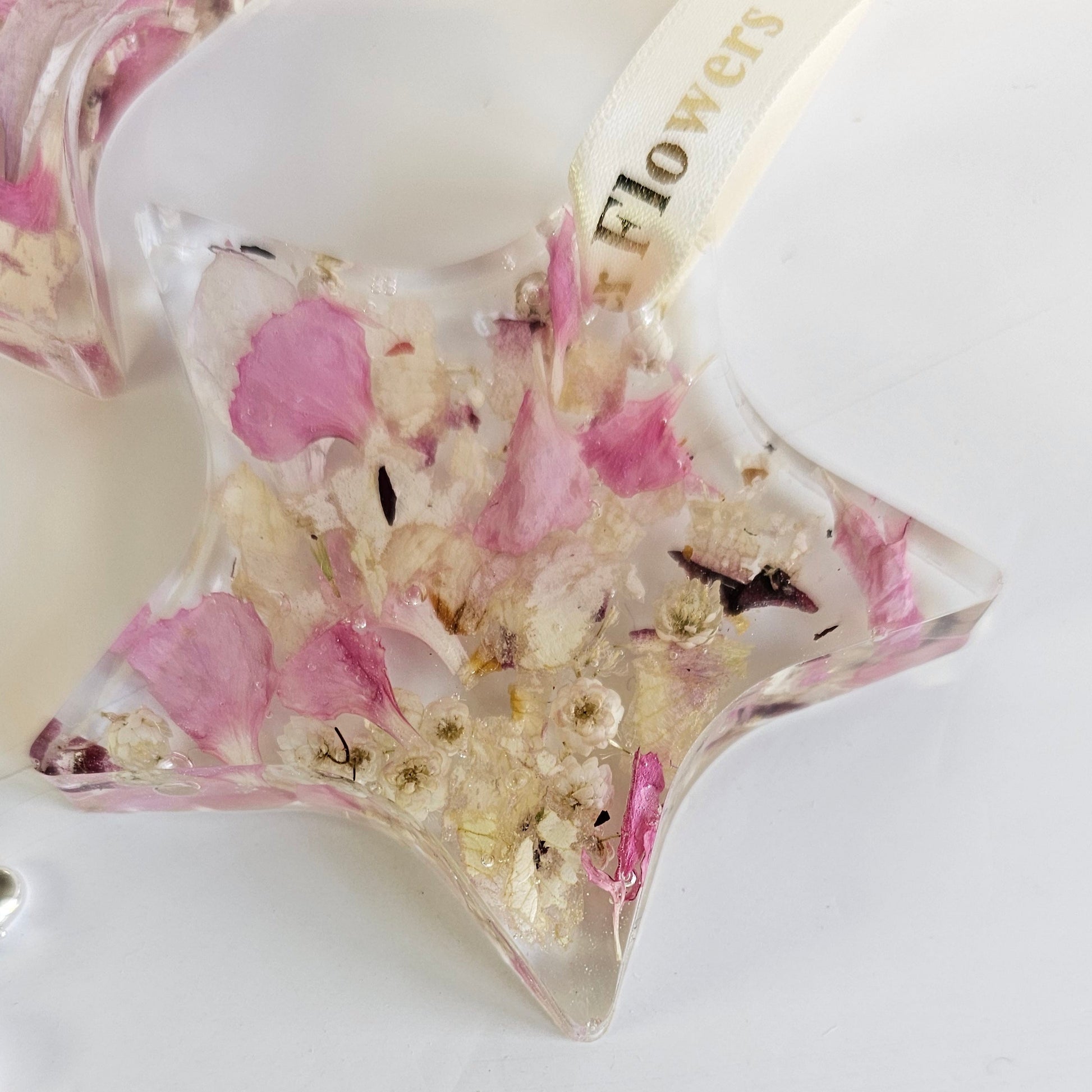Star-shaped decorative resin item with pink and white flowers on a white background